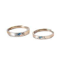Pair of silver couple's rings from Spacewallart, showcasing polished, intertwined designs on a neutral background.