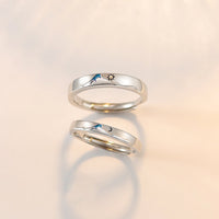 Pair of silver couple's rings from Spacewallart, shown close-up on a white background, showcasing their smooth, polished finish.